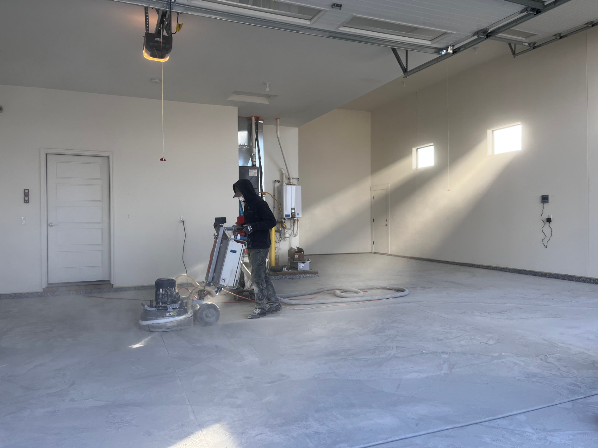 Contractor diamond grinding a concrete garage floor during coating prep